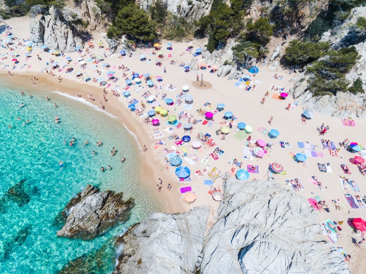Colorful umbrellas and people lying on beach taken from the sky