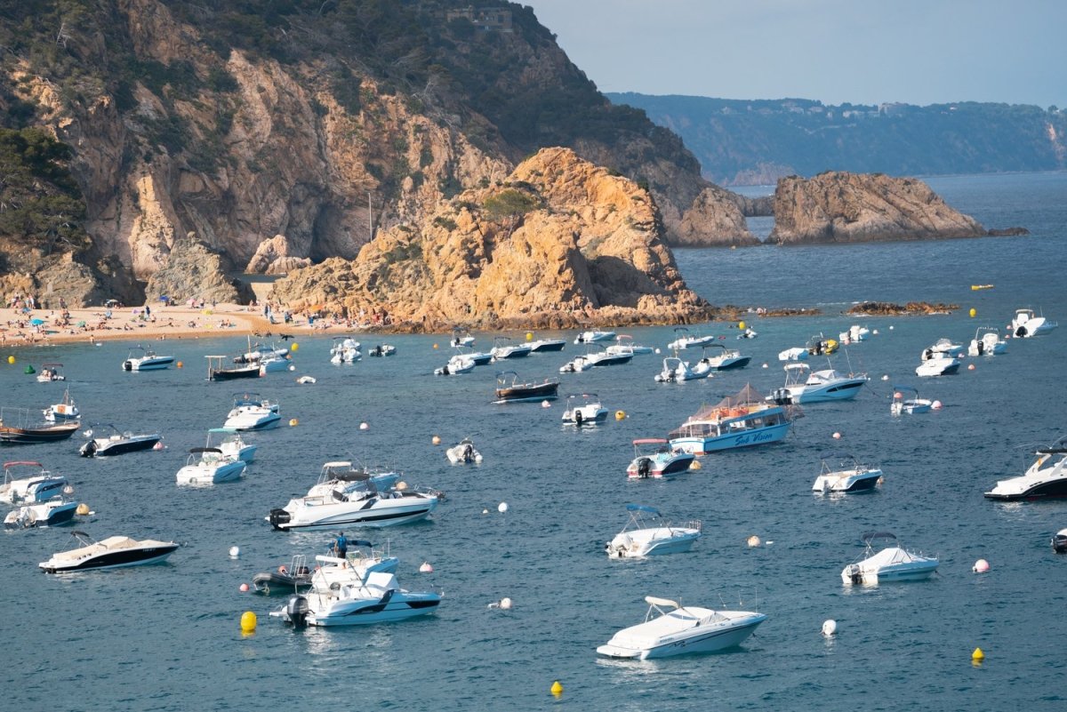 Many boats anchored off in ocean along Tossa de Mar beach in Spain