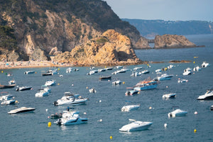 Many boats anchored off in ocean along Tossa de Mar beach in Spain