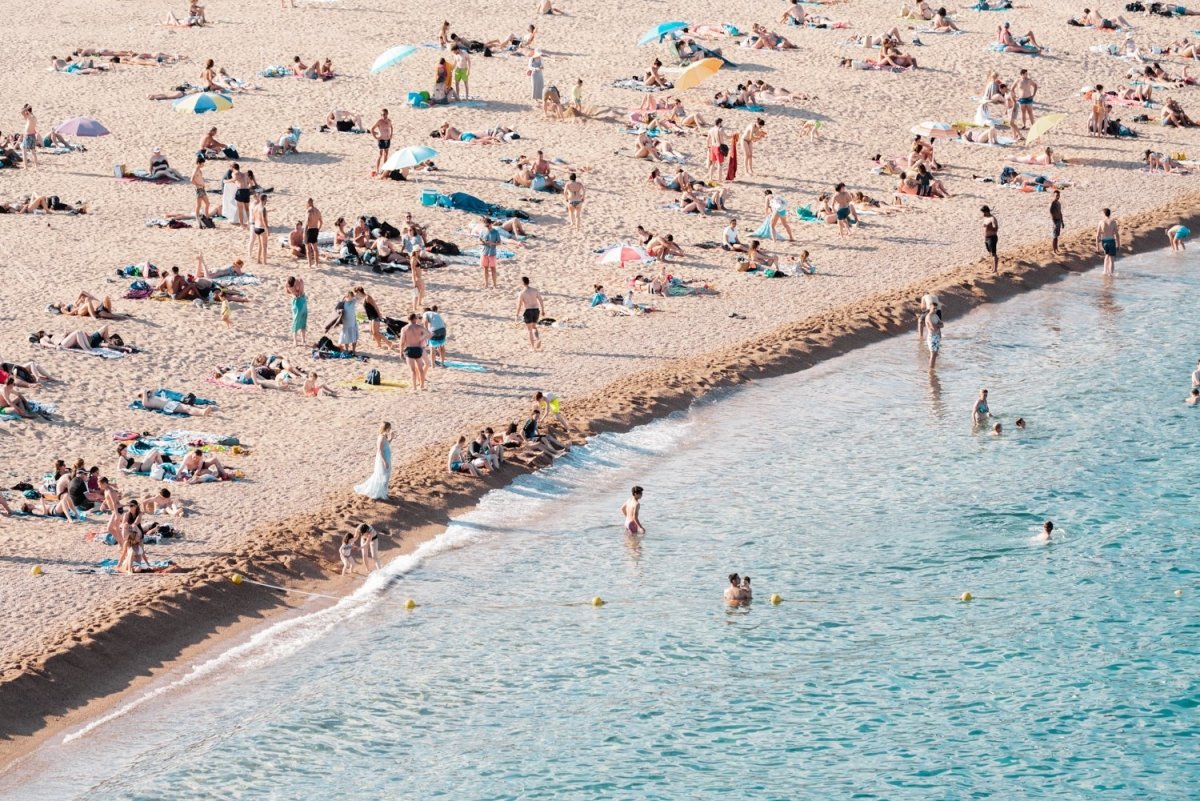 People lying on beach along calm blue sea