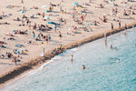 People lying on beach along calm blue sea