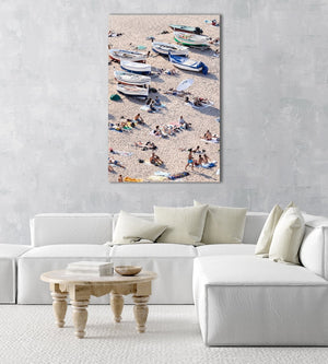 People lying on sand next to boats in an acrylic/perspex frame