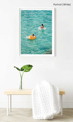 Young girl and woman floating on round lilos in turquoise sea in a white fine art frame