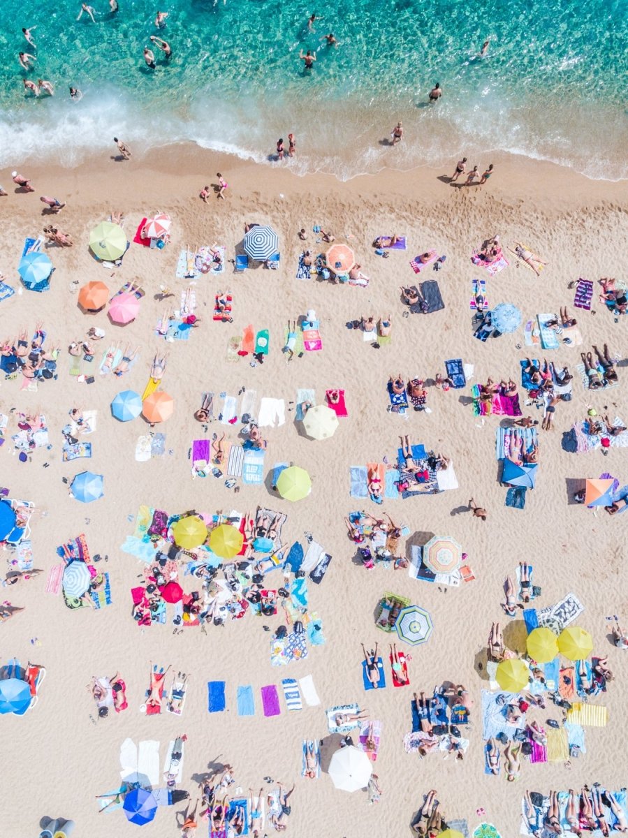 Very crowded Lloret de Mar beach from above with blue water, colorful towels and umbrellas