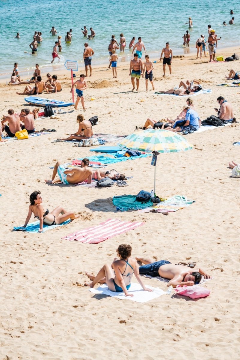 People tanning, swimmers and umbrellas at a beach in Cascais Portugal
