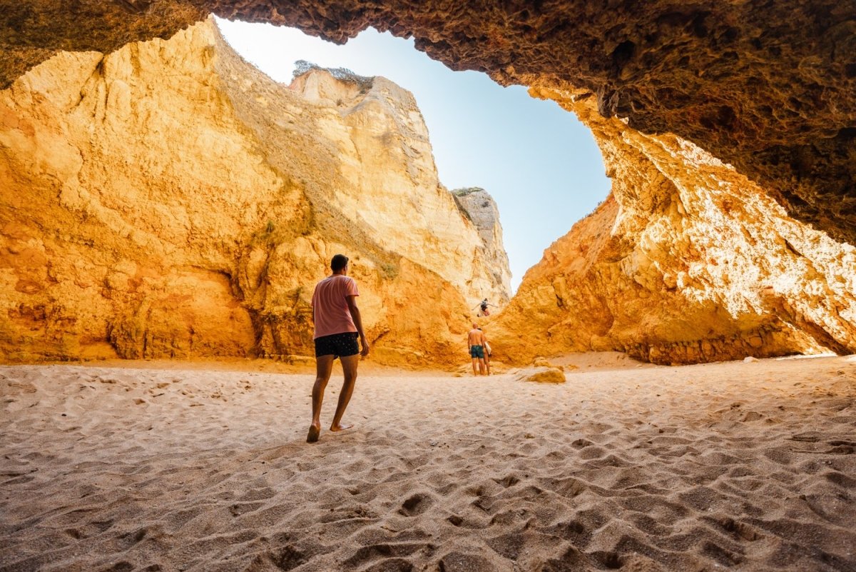 Man walking in a big yellow cave in Praia Dona Ana beach in Lagos