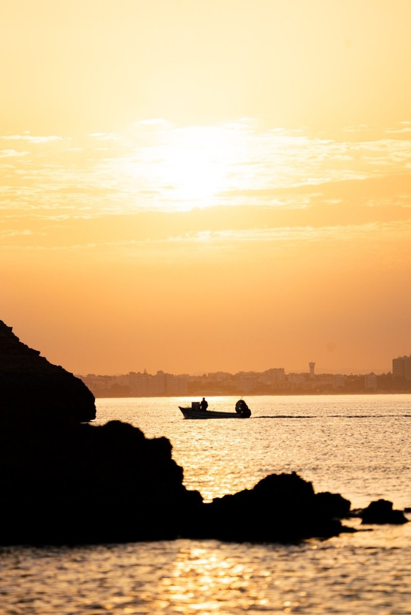 Orange sunrise with a boat cruising past Lagos coastline