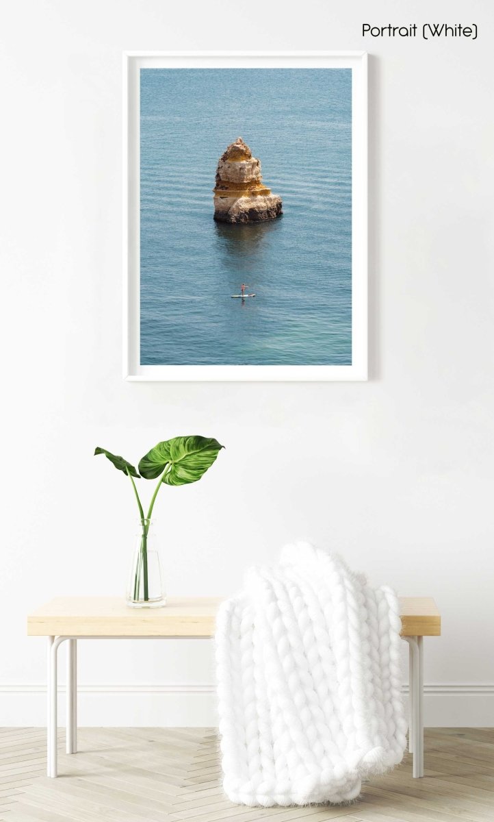 Woman on a SUP paddling near big cliff in Lagos in a white fine art frame