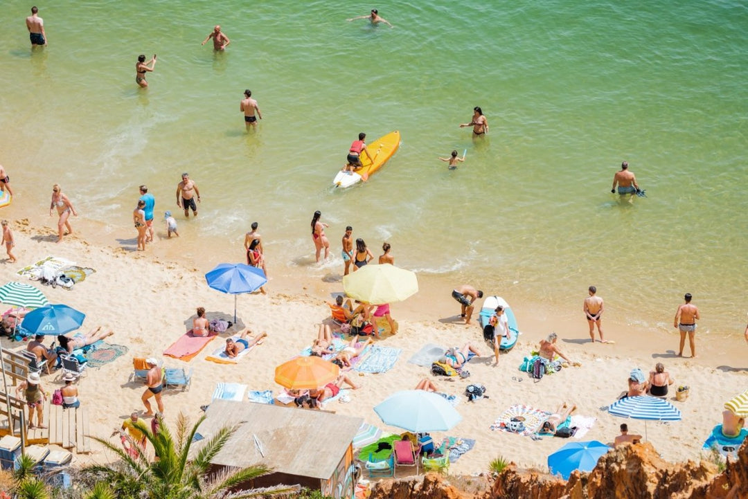 Colorful boards, people, water and sand on Praia do Camilo Lagos