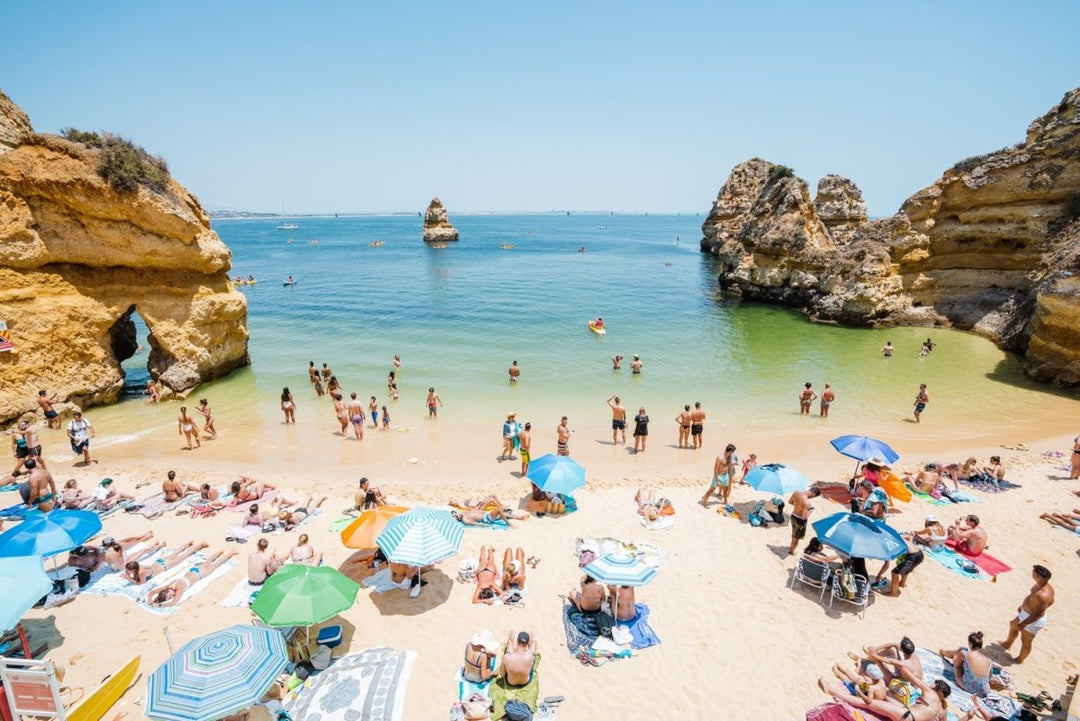 Busy Camilo beach with cliffs, people and calm green water