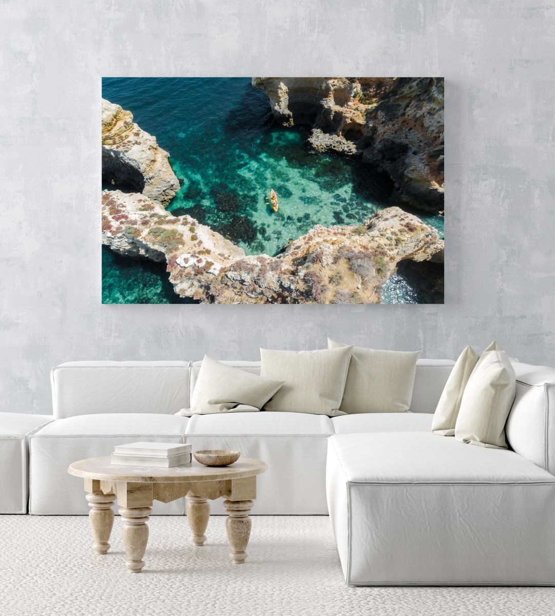 Aerial of two people paddling yellow kayak near Lagos caves in ocean in an acrylic/perspex frame