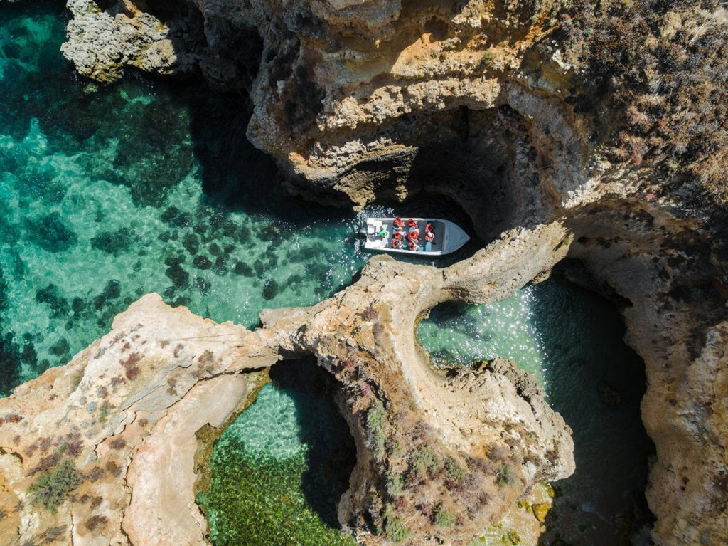 Aerial of a tour boat in caves along Ponta da Piedade