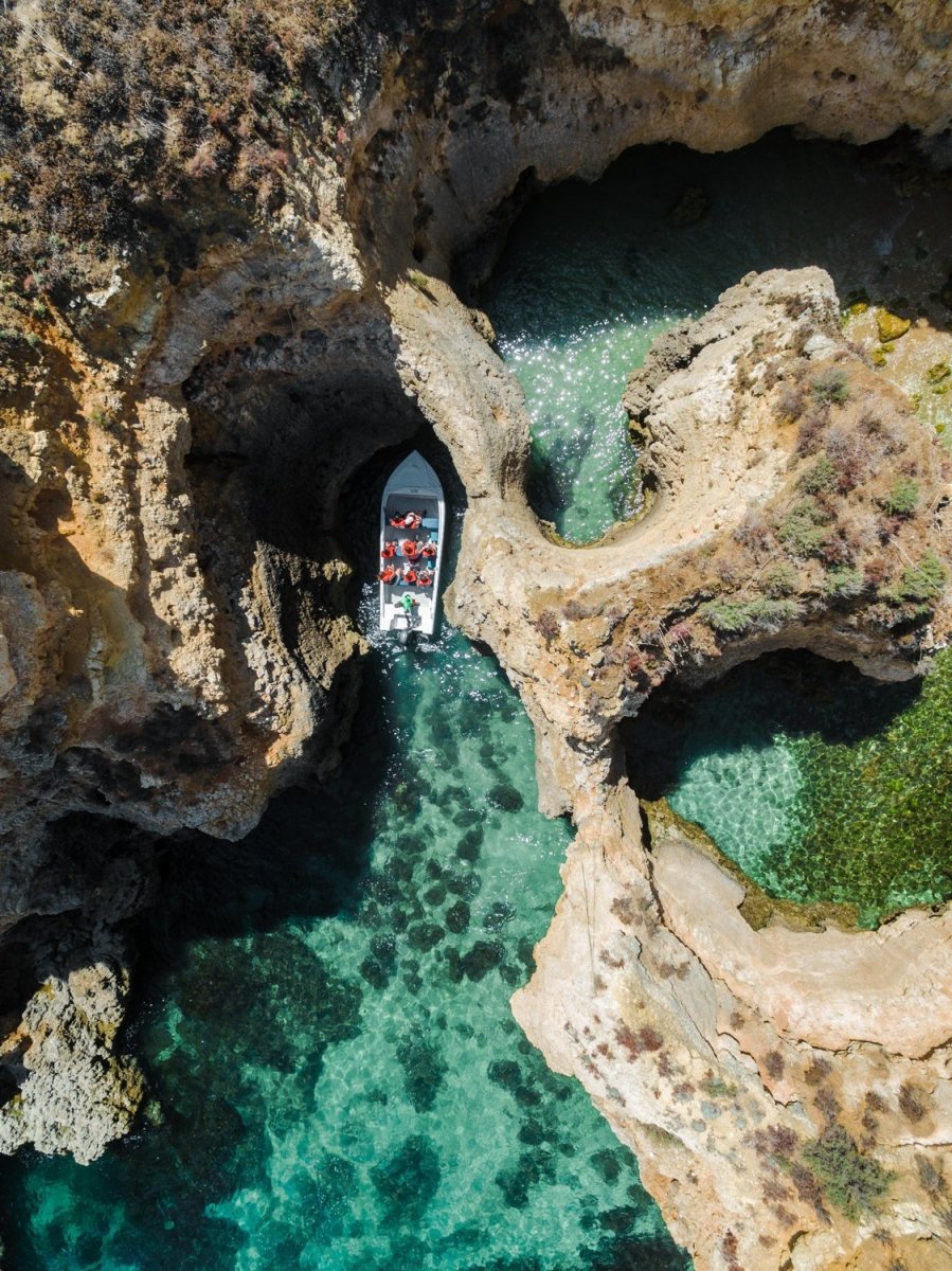 Aerial of a tour boat in caves along Ponta da Piedade