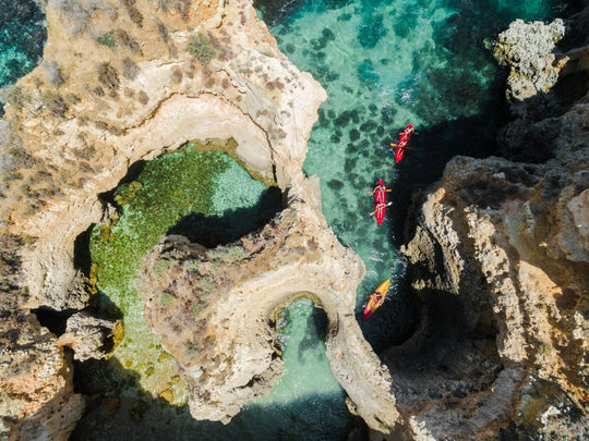 Three kayaks following each other through caves from above