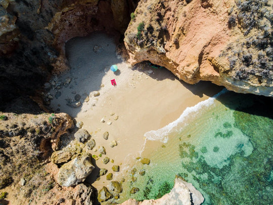 Woman lying with umbrella at cliffs on a secret beach in Lagos