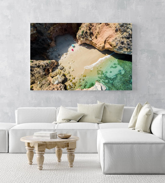 Woman lying with umbrella at cliffs on a secret beach in Lagos