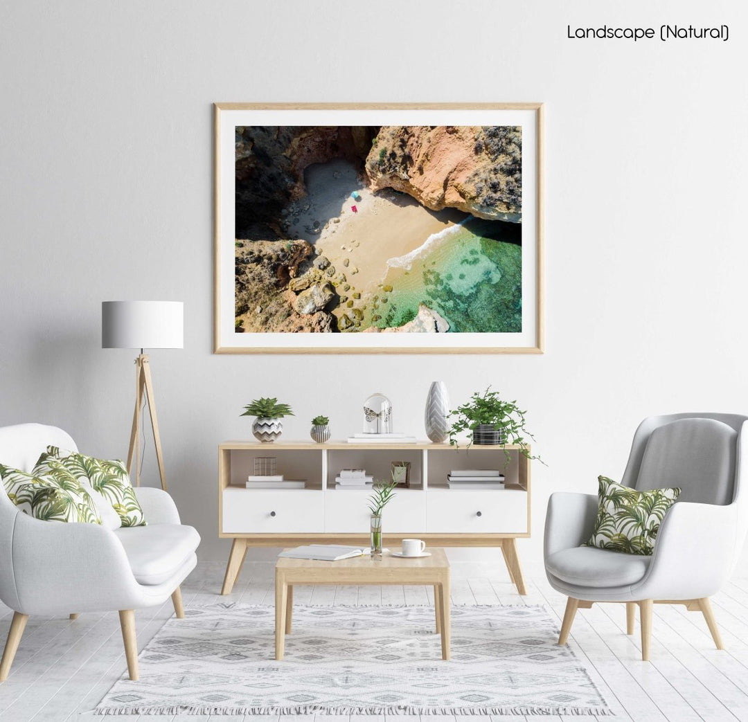 Woman lying with umbrella at cliffs on a secret beach in Lagos in a natural fine art frame