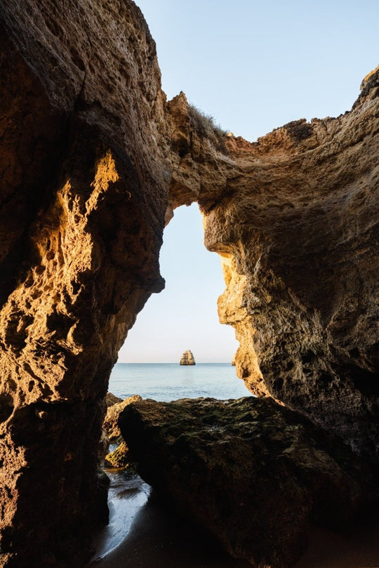 Inside a cave in Lagos looking out to blue sea and rock