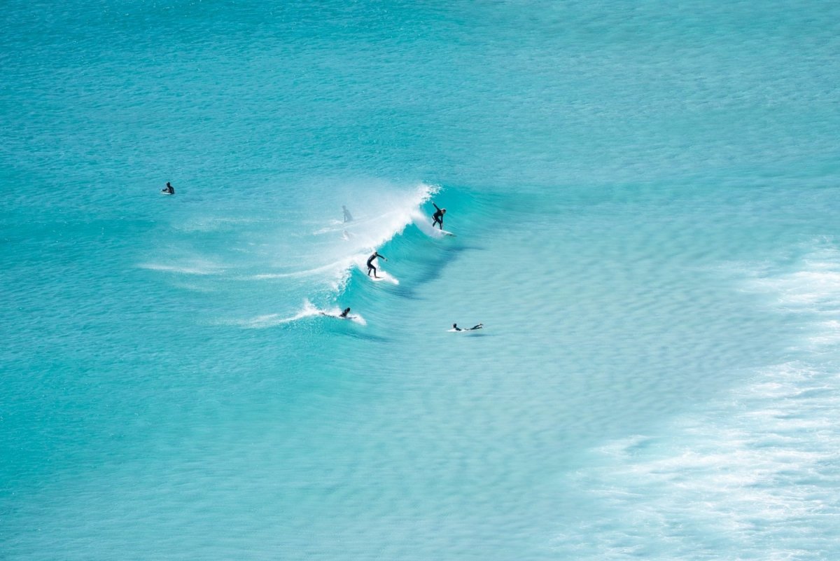 Surfers in Llandudno, Cape Town, on a wave breaking in the middle of blue water.