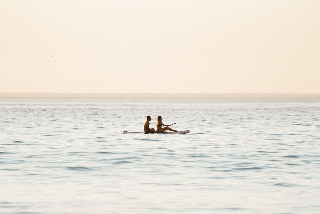 Two people sitting on a SUP in the ocean