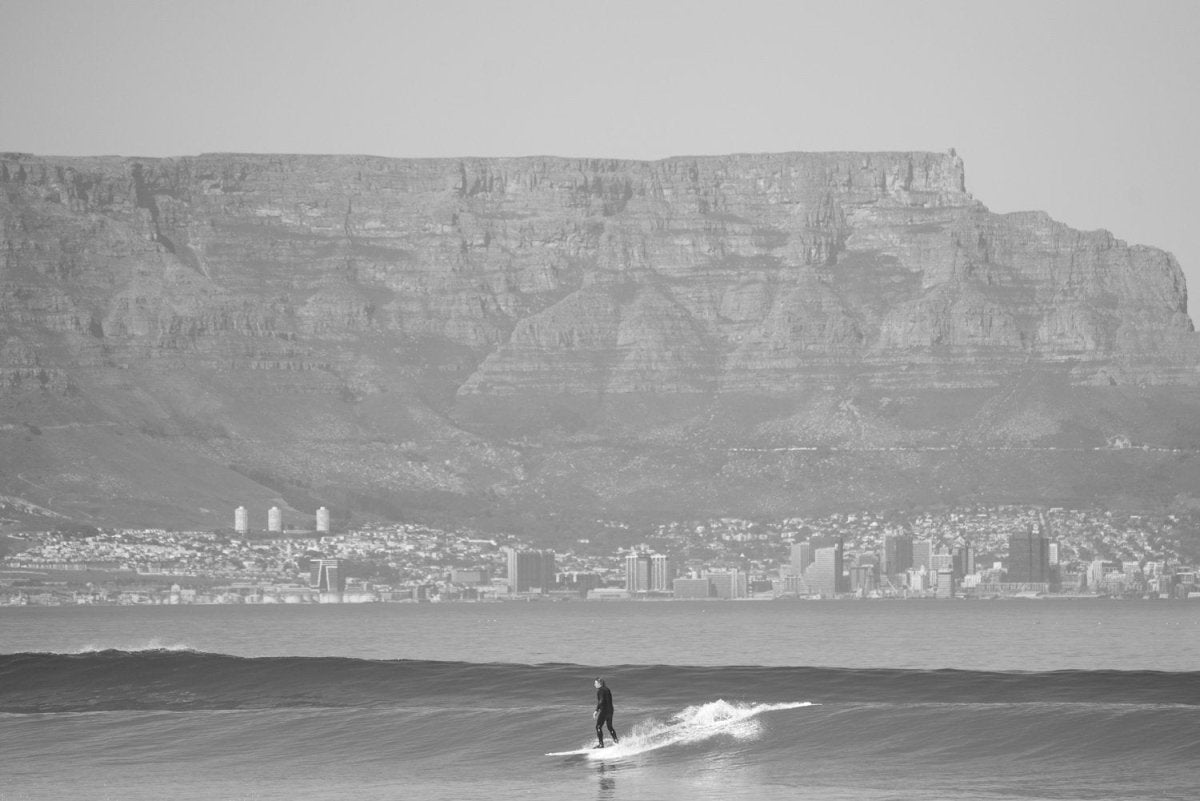 Surfer in black and white beneath Table Mountain