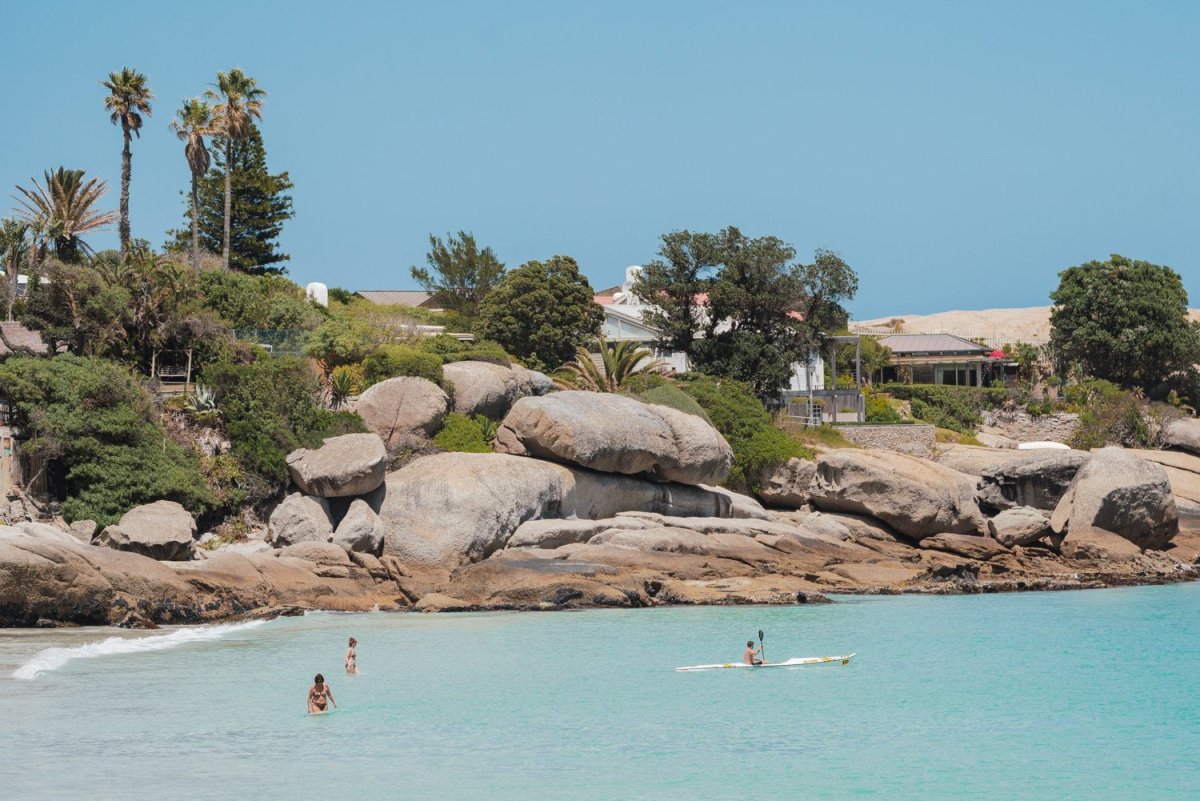 Photography of a clear sunny day at clifton with swimmers and kayak