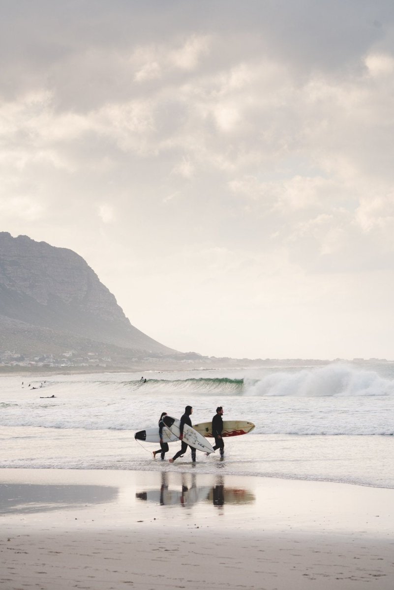 Three surfers walking at Betty's Bay Beach