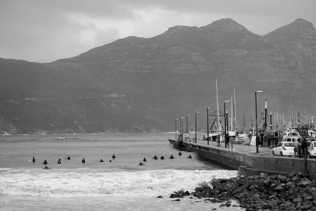 Hout Bay harbour wall surfers on a stormy day