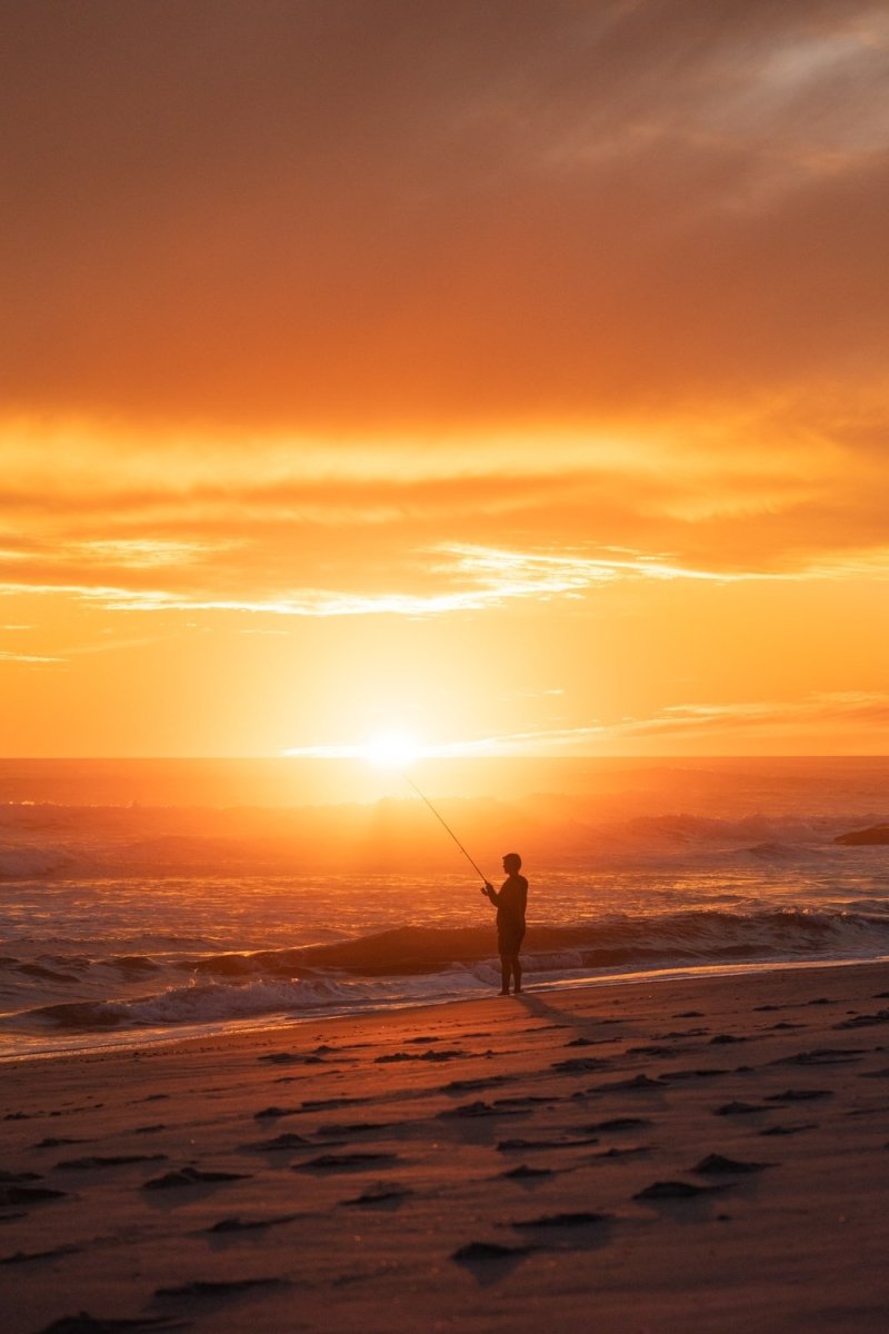Person fishing with beautiful orange sunset