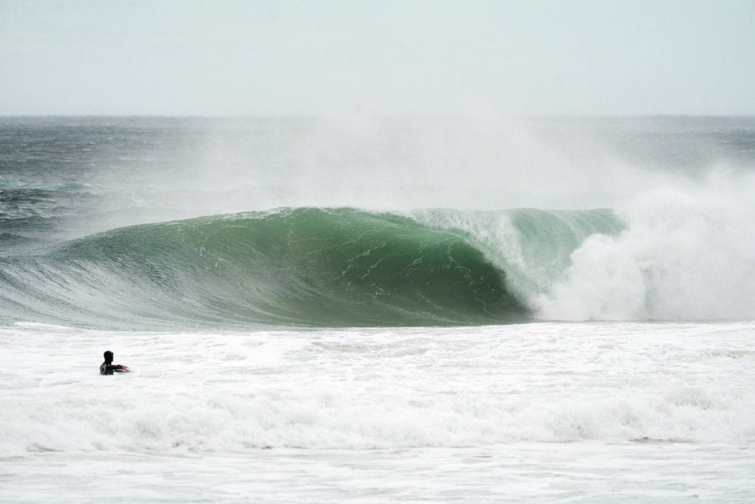 Big grey wave with person watching from water