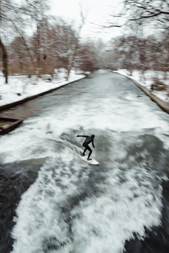 Man surfing river wave in the city during snowfall in munich.