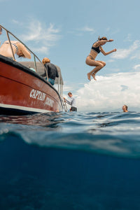 Girl jumping off boat in Bali, Indonesia on Nusa Lembongan island.